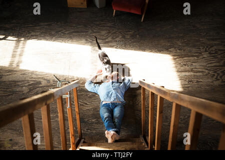 High angle view of man playing with domestic cat while lying on floor at home Stock Photo