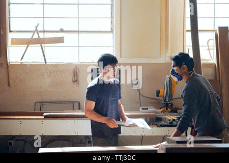 Carpenters discussing plan in workshop Stock Photo