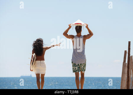 Woman pointing while standing with boyfriend at beach Stock Photo