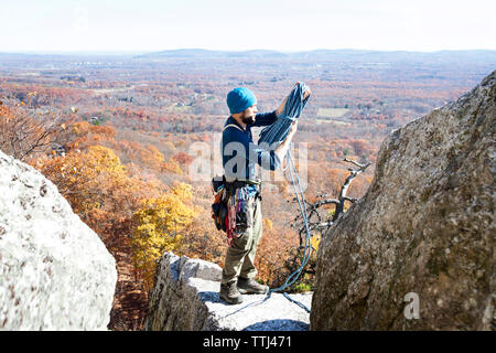 Man holding climbing rope while standing on rock Stock Photo