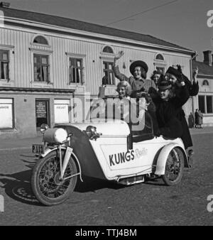 Driving in the 1940s. A man drives a three wheeled motorcycle and a group of women have joined the ride. Sweden 1943 Kristoffersson Ref A41-5 Stock Photo