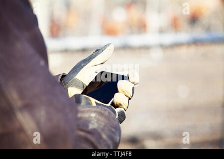 Cropped hands of worker using mobile phone at construction site Stock Photo