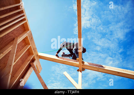 Low angle view of worker making construction frame against blue sky Stock Photo