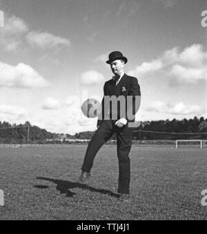 1940s soccer player. A gentleman dressed in a suit and a bowler hat is kicking a football in the air. Sweden 1944 Kristoffersson F104-1 Stock Photo