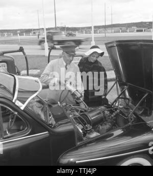 Car owner of the 1950s. A woman has stopped at a service station and is getting assistance of a man filling more engine oil.  Sweden 1954. Kristoffersson ref BP35-11 Stock Photo