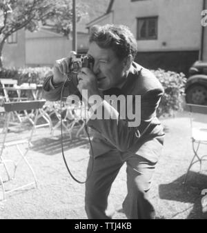 Amateur photographer in the 1950s. A young man is aiming to take a picture of something or someone with his camera. He is american actor Burgess Meredith taking a picture. Sweden 1954. Photo Kristoffersson Ref BF78-1 Stock Photo