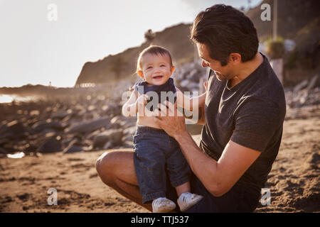 Father with cheerful baby boy at beach Stock Photo