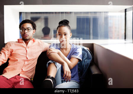 Portrait of couple sitting on sofa at home Stock Photo