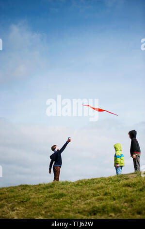 Low angle view of children looking at man flying kite Stock Photo