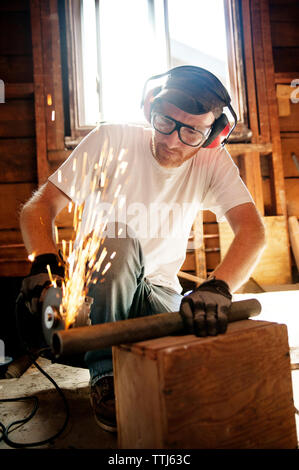 Carpenter cutting iron with circular saw in workshop Stock Photo