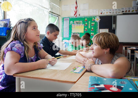 Teacher looking at children learning in school Stock Photo