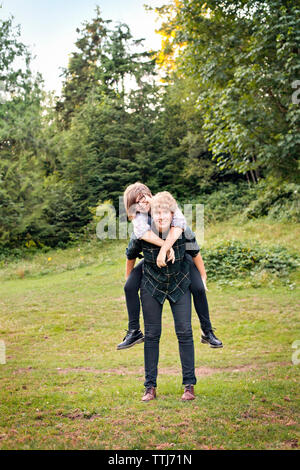 Portrait of couple piggybacking while standing on field Stock Photo