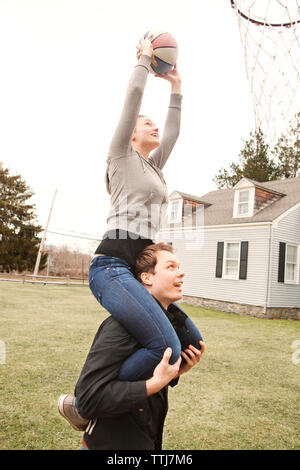 Man carrying woman while playing basket ball Stock Photo