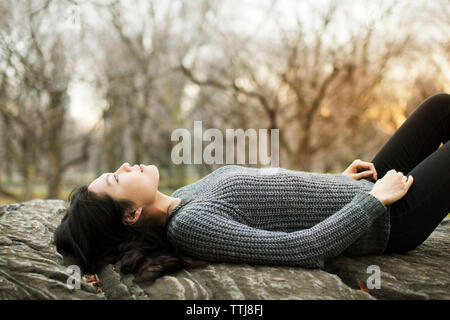 Thoughtful woman relaxing on rock Stock Photo