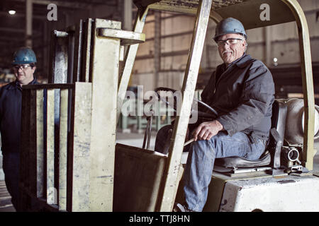 Portrait of man sitting on forklift in factory Stock Photo