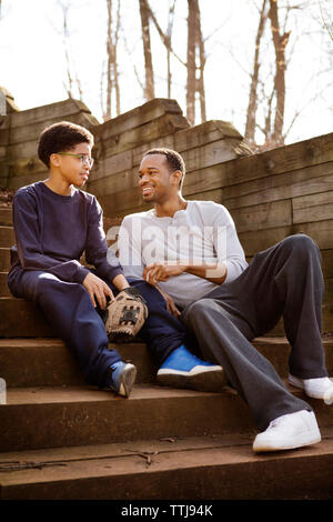Father and son talking while sitting on steps Stock Photo