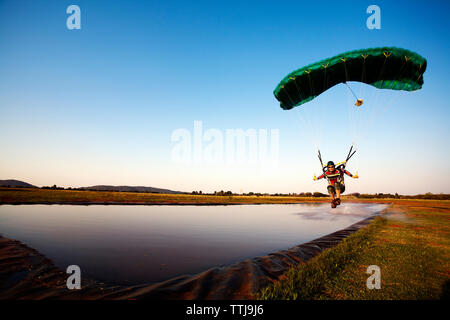 Man parasailing over lake against clear sky Stock Photo