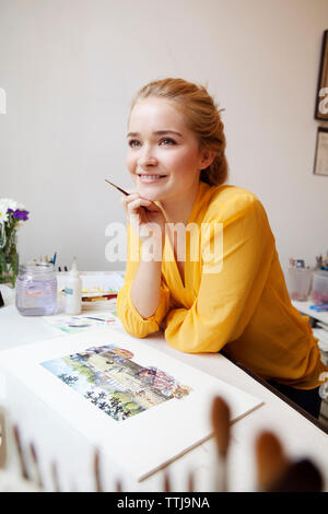 Woman looking away while standing at studio Stock Photo