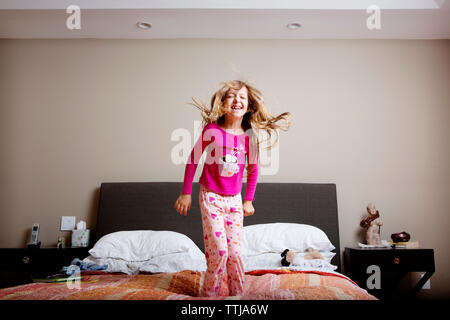 Girl jumping on bed at home Stock Photo