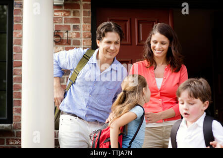 Happy family standing against front door Stock Photo