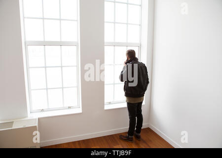 Man using mobile phone while sitting with son at window in home Stock Photo