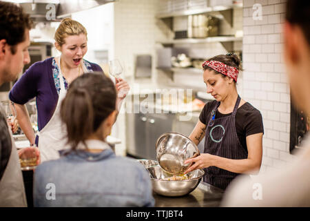 Female chef teaching while standing at table in commercial kitchen Stock Photo