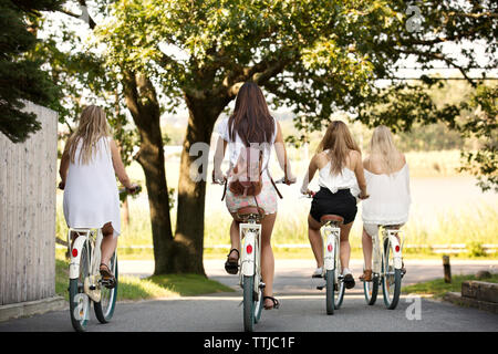 Rear view of women cycling on road Stock Photo