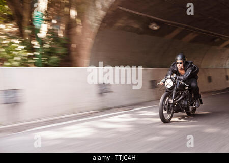 Man wearing sunglasses riding motorcycle on road Stock Photo