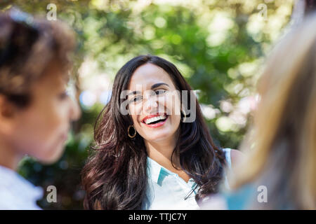 Woman laughing while standing by friends Stock Photo