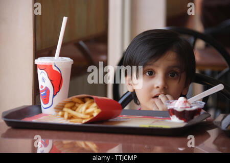 Girl eating ice cream with french fries in a restaurant Stock Photo