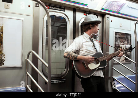 Street musician playing guitar in subway train Stock Photo