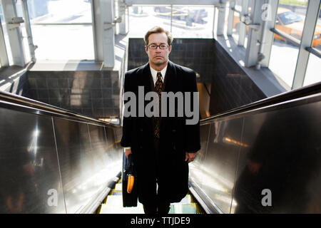 Portrait of businessman standing on escalator Stock Photo