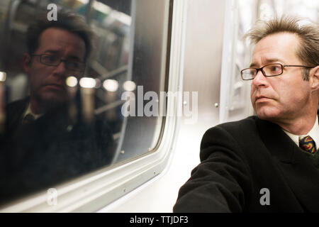 Thoughtful businessman traveling in train Stock Photo