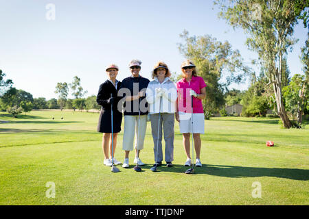 Portrait of happy friends standing at golf course Stock Photo