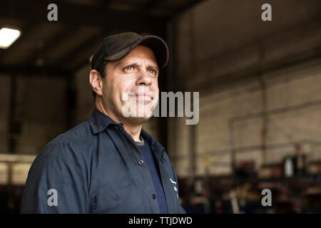 Portrait of mechanic standing by bus in repair shop Stock Photo