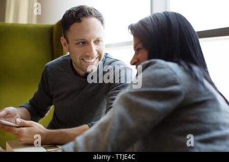Colleagues laughing while sitting in office Stock Photo
