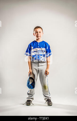 Portrait of baseball player with cap in hand against white background Stock Photo