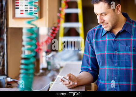 Man using mobile phone while standing in carpentry workshop Stock Photo