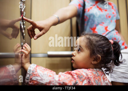 Woman pressing push button while daughter looking in elevator Stock Photo