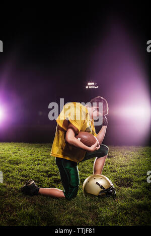 Depressed football player holding ball on field Stock Photo