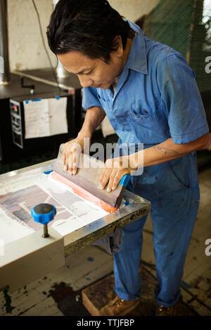 High angle view of man pressing ink on frame in workshop Stock Photo