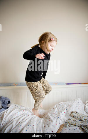 Playful girl jumping on bed at home Stock Photo