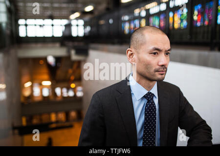 Thoughtful businessman looking away while standing at railroad station Stock Photo
