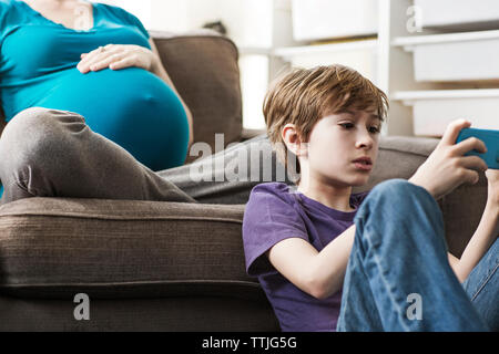 Boy using smart phone while sitting on floor at home Stock Photo
