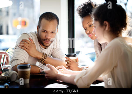 Colleagues using tablet computer while sitting at cafe Stock Photo