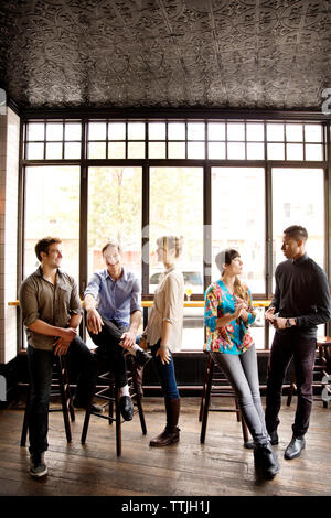 Friends talking while relaxing in bar Stock Photo