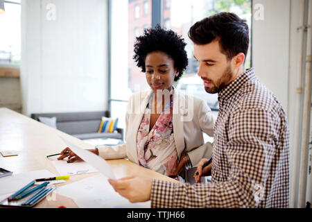 Colleagues discussing document while working in office Stock Photo