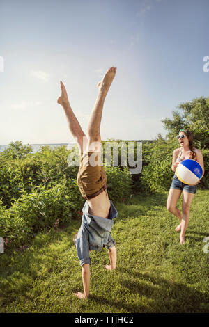 Cheerful woman looking at man doing handstand in backyard Stock Photo