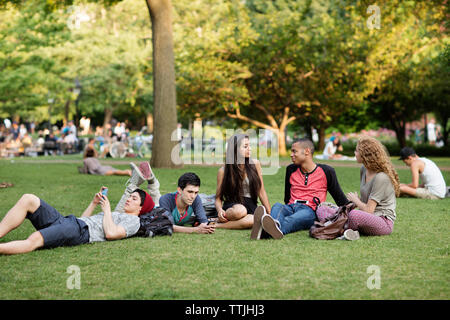 Friends relaxing on field in campus Stock Photo