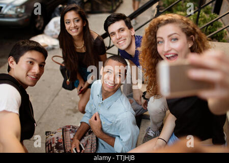 High angle view of woman taking selfie with friends while sitting on steps Stock Photo